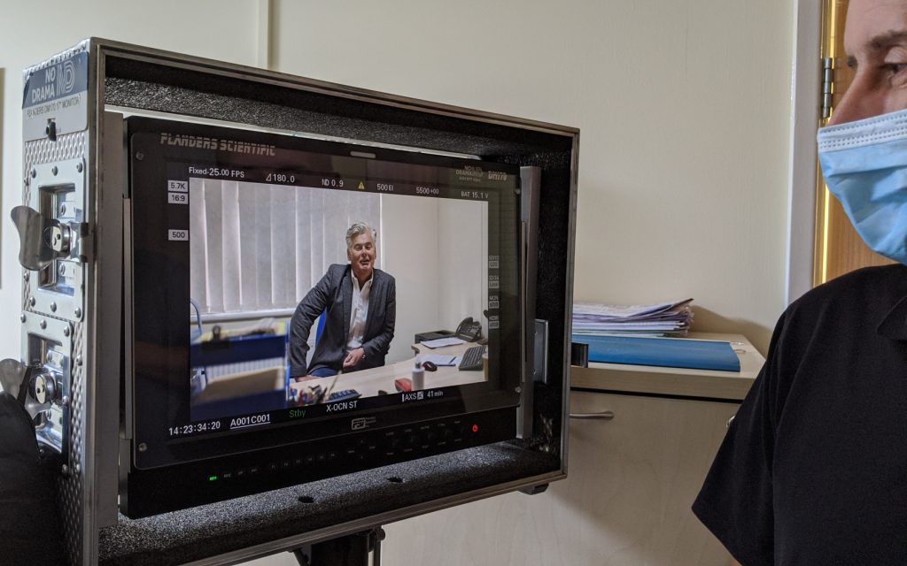 Monitor and masked camera man at LED product testing at Power Gems in Manchester